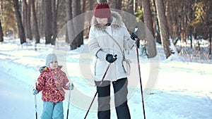 Senior woman and girl nordic walking in winter park