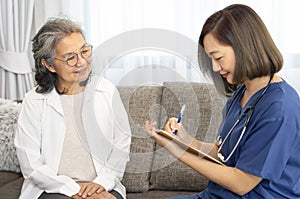 A senior woman giving a health interview to a home visiting nurse