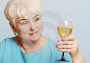 Senior woman with glass of white wine.