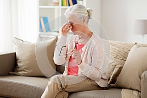 Senior woman with glasses having headache at home
