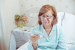 Senior woman in glasses, reading pills.