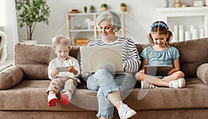 Senior woman with grandchildren using gadgets at home