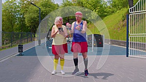 Senior woman grandmother trainer teaching old grandfather with sport weightlifting fitness exercises