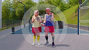 Senior woman grandmother trainer teaching old grandfather with sport weightlifting fitness exercises