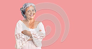 Senior woman with gray hair wearing bohemian style happy face smiling with crossed arms looking at the camera