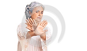 Senior woman with gray hair wearing bohemian style rejection expression crossing arms doing negative sign, angry face