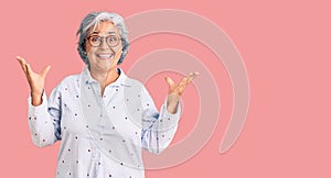 Senior woman with gray hair wearing casual business clothes and glasses celebrating mad and crazy for success with arms raised and