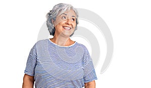 Senior woman with gray hair wearing casual striped clothes looking away to side with smile on face, natural expression