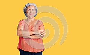 Senior woman with gray hair wearing orange tshirt happy face smiling with crossed arms looking at the camera