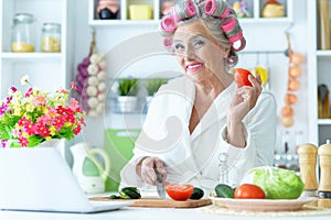 Senior woman in hair rollers at kitchen