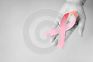 The senior woman hand in black and white supports Breast Cancer Day by holding Pink Ribbon Breast Cancer Awareness with copy space