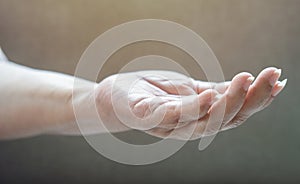 Senior woman hand over light beige background picking and taking invisible thing, holding object with fingers showing space