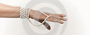 Senior woman hand with Pearl necklace cut out on white. Luxury jewelry on female hand with French manicure. Close up