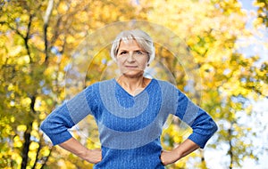 Senior woman with hands on hips in autumn park