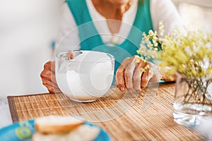 Senior woman hands holding big cup of yogurt. Old woman holding a glass of milk, health care concept, wrinkled skin, no