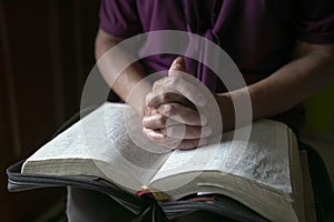 Senior woman hands on open bible, praying