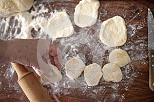 Senior woman hands rolling out dough in flour with rolling pin in her home kitchen