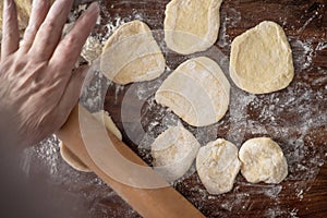 Senior woman hands rolling out dough in flour with rolling pin in her home kitchen