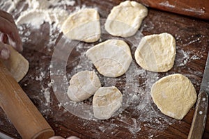 Senior woman hands rolling out dough in flour with rolling pin in her home kitchen