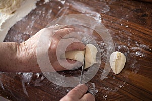 Senior woman hands rolling out dough in flour with rolling pin in her home kitchen