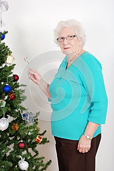 Senior woman hanging candy cane on christmas tree