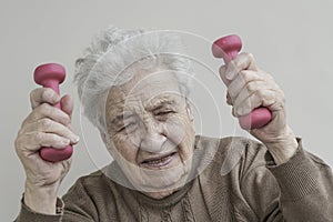 Senior woman has difficulty to lifting dumbbells