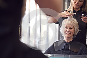 Senior Woman Having Hair Cut By Female Stylist In Hairdressing Salon