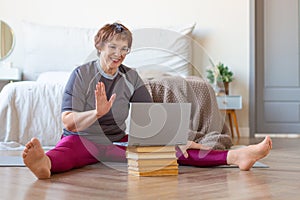 Senior woman having online meeting with a trainer online before a Pilates workout.