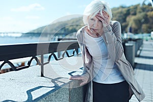 Senior woman having vertigo outdoors photo