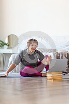 Senior woman having video call with a trainer online before a Pilates workout.