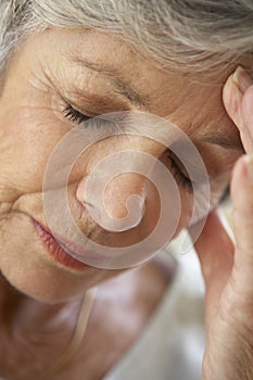 Senior Woman With Head In Hands Looking Weary