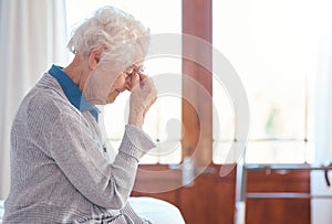 Senior woman, headache and stress with anxiety in retirement house, lonely and sad with mental health. Elderly female
