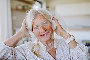 Senior woman with headphones listening to relaxation music at home