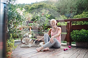 A senior woman with headphones outdoors on a terrace, resting after exercise.