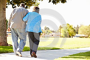 Senior Woman Helping Husband As They Walk In Park Together