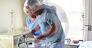 Senior woman helping man to walk with walker