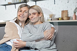 Senior woman and her adult daughter hugging and smiling