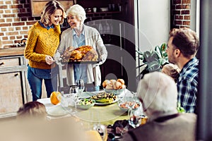 senior woman and her daughter carrying turkey for thanksgiving dinner with their