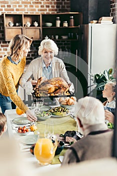 senior woman and her daughter carrying turkey for thanksgiving dinner with their