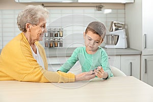 Senior woman with her grandson using digital glucometer. Diabetes control