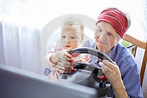 Senior woman and her great granddaughter enjoying car racing video game on laptop