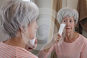 A senior woman in her sixties is doing some deep pore cleaning