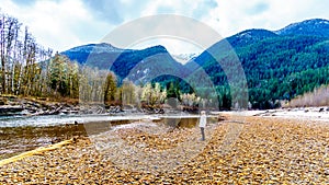 Senior woman on a hike along the Iron Oxide Stained rocks lining the shore of the Squamish River in British Columbia, Canada