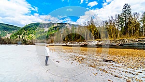 Senior woman on a hike along the Iron Oxide Stained rocks lining the shore of the Squamish River in British Columbia, Canada