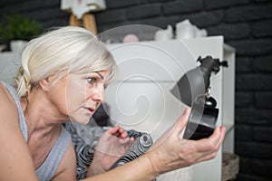 Senior woman holding alarm clock checking out time