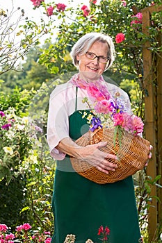 Senior woman holding basket full of flowers