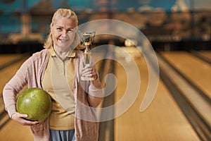 Senior Woman Holding Bowling Ball and Trophy