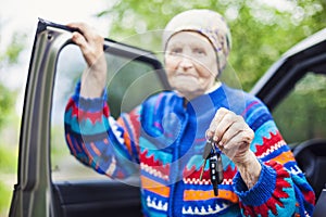 Senior woman holding car key and smiling, selective focus