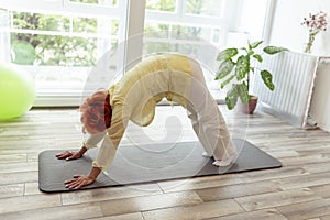 Senior woman holding downward facing dog yoga position