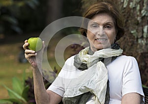 Senior Woman Holding a Fresh Apple Under the Tree